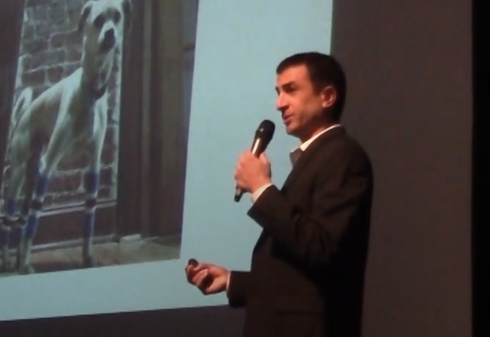 Paul Smith Rivas speaking in an auditorium with a slideshow